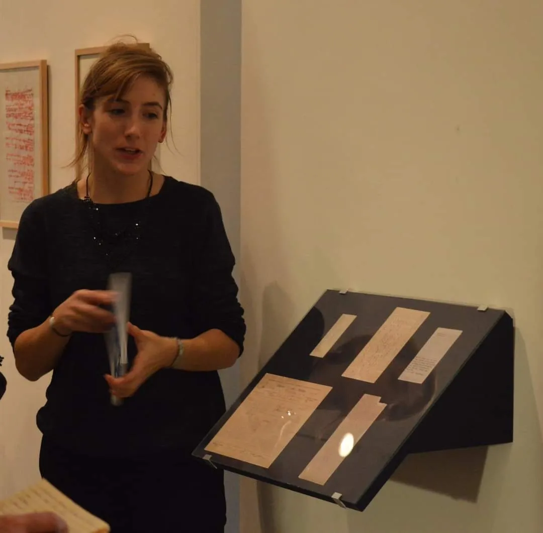 Vanessa Noizet présentant un document près d’une vitrine lors d’une exposition.
