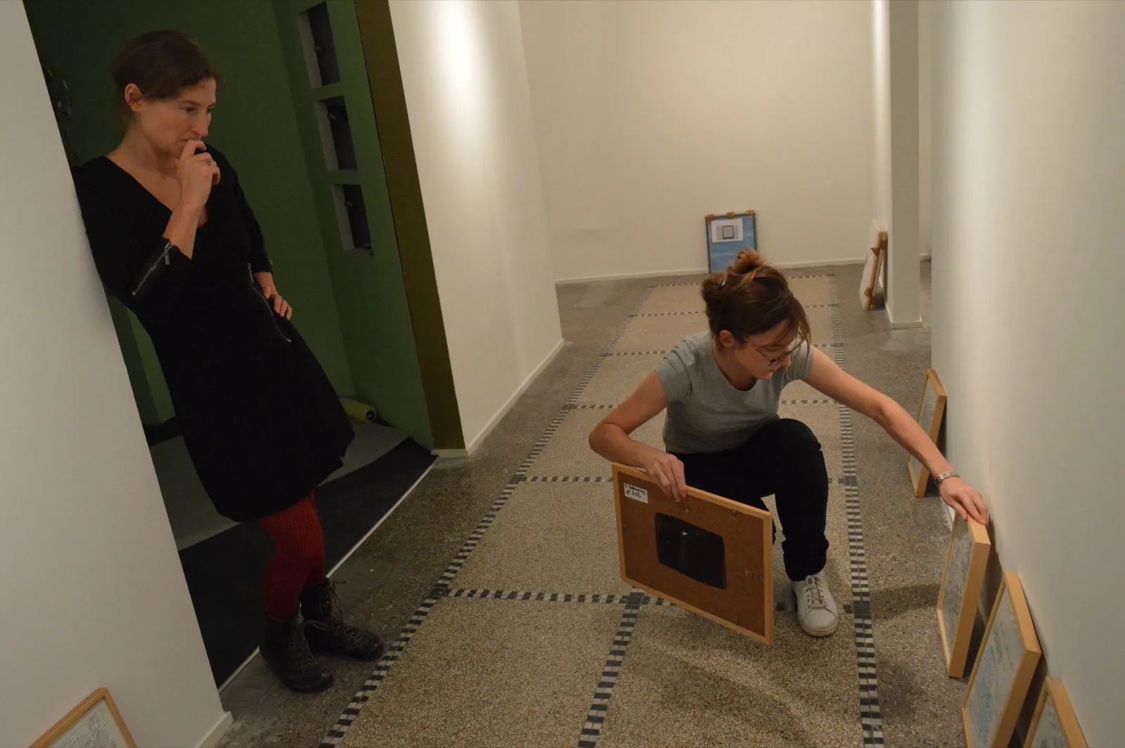 Montage d’une exposition : accrochage d’œuvres encadrées.